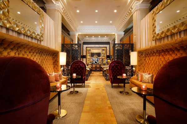 Relax in the elegant lobby, featuring plush seating and a grand mirror.