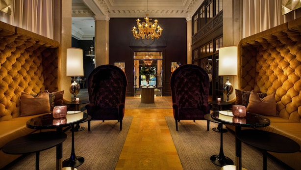 En lyxig lobby med en storslagen kristallkrona, bekväma sittplatser och ett välpolerat golv.
