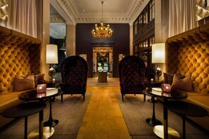 Eine luxuriöse Lobby mit einem prunkvollen Kronleuchter, komfortablen Sitzgelegenheiten und einem glänzenden Boden.