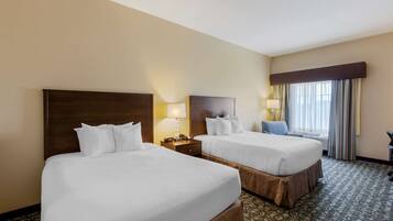 A hotel room with two beds, a nightstand with a lamp, a chair, and a large window with curtains.