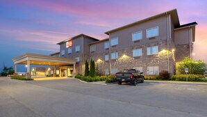Un hotel a più piani con una stazione di servizio, un parcheggio e un camion parcheggiato di fronte.