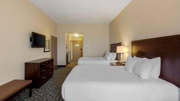 A hotel room with two beds, a TV, a desk, and a lamp.