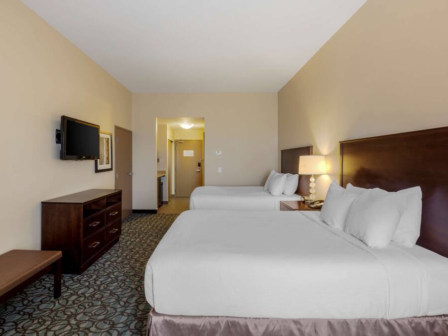 A hotel room with two beds, a TV, a desk, and a lamp.