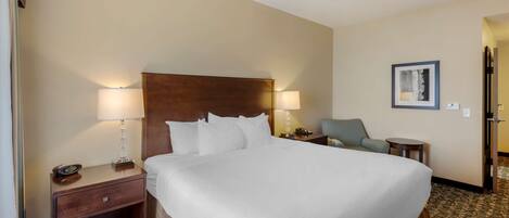 A hotel room with a large bed, two bedside tables with lamps, a chair, and a small table.