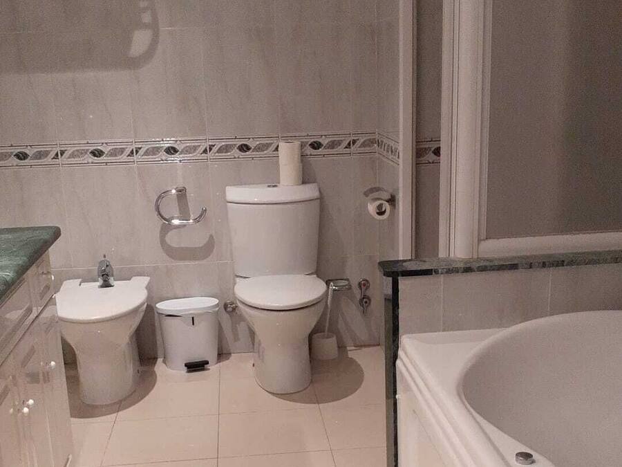 A modern bathroom with a bathtub, two toilets, a bidet, and a vanity with a mirror.