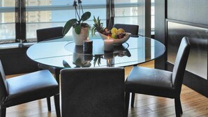 Un'elegante sala da pranzo con un tavolo rotondo, sedie nere, una pianta in vaso e una ciotola di frutta fresca.
