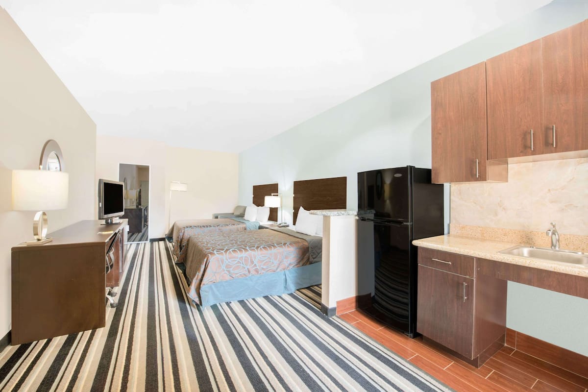 Een hotelkamer met een bed, een bureau, een televisie, een koelkast en een kitchenette.