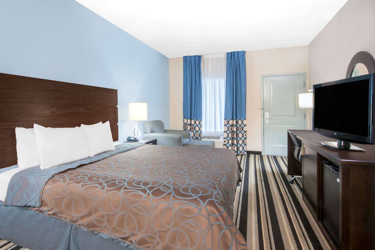Een hotelkamer met een groot bed, een televisie, een bureau en een deur.