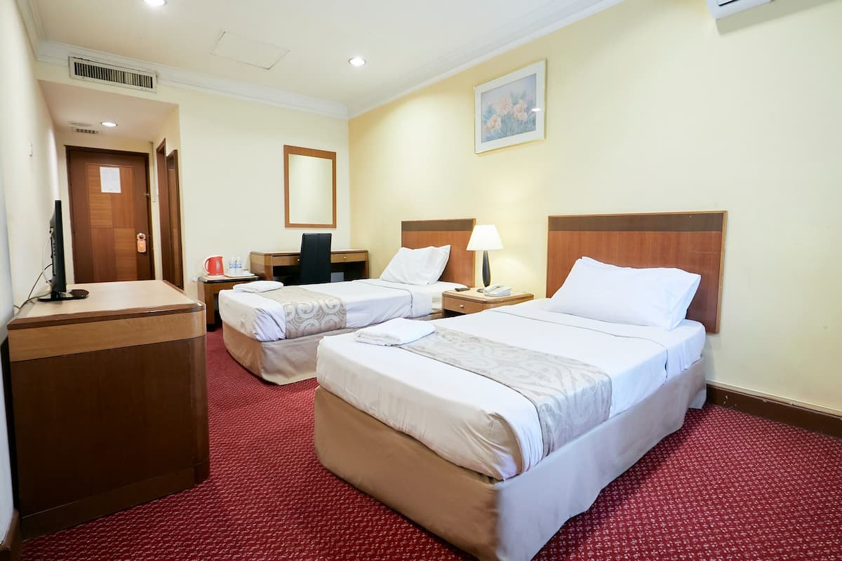 A hotel room with two beds, a desk, a chair, a TV, and a painting on the wall.