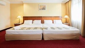 A double room with two beds, a wooden headboard, a painting on the wall, and a red carpet. - Grand Pacific Hotel PWTC (Kuala Lumpur)