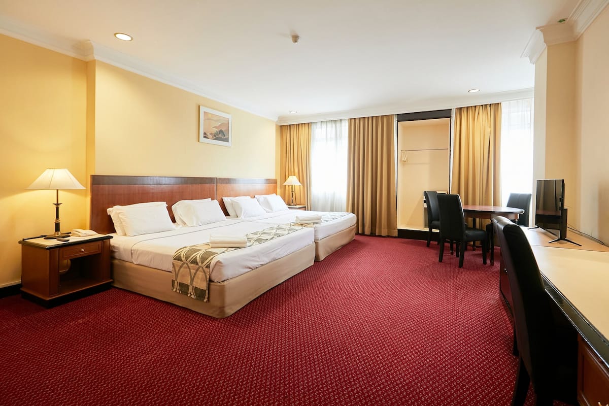 A hotel room with a large bed, a desk, a chair, and a TV.