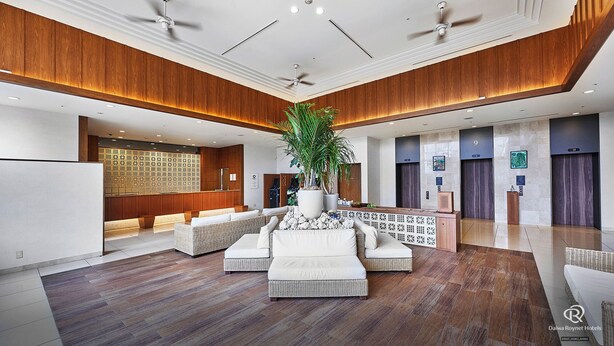 A spacious lobby with a reception desk, seating area, and a large potted plant.