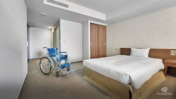 Habitación de hotel con una cama grande, una silla de ruedas y un armario de madera.
