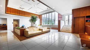 A modern hotel lobby with a reception desk, a seating area with a sofa, a staircase, and large windows. - Daiwa Roynet Hotel Naha - Omoromachi (Naha)