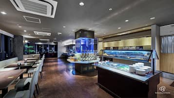 A modern hotel lobby with a buffet area, seating arrangements, and a view of the cityscape.