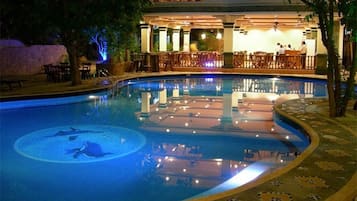 Een buitenzwembad, ligstoelen bij het zwembad