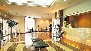 A spacious lobby with a reception desk, a seating area, and a large plant. - Hotel Excel Okayama (Okayama)