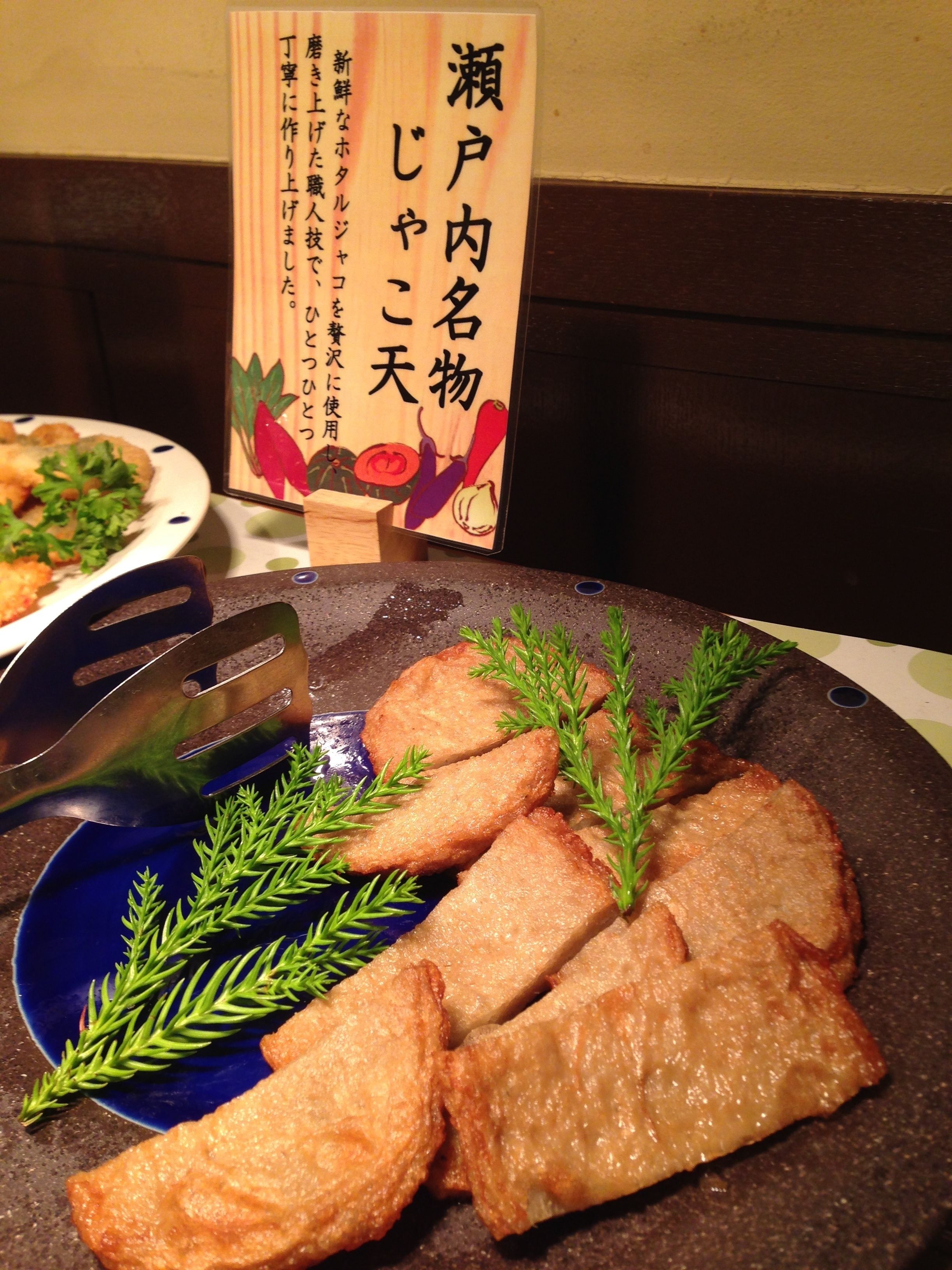 Ein Teller mit frittiertem Essen, garniert mit grünen Kräutern, eine Gabel und eine Speisekarte mit japanischem Text.