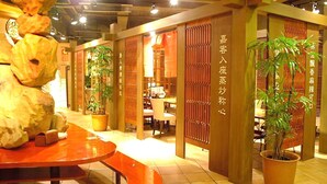 A modern interior with a curved wooden table, potted plants, and traditional decor elements. - Hotel Excel Okayama (Okayama)
