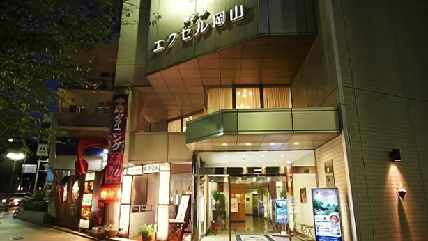 A hotel entrance with a glass facade, illuminated signage, and a visible entrance door. - Hotel Excel Okayama (Okayama)