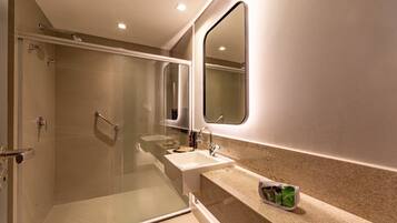 Un baño moderno con ducha de mampara de vidrio, lavabo y espejo de tocador.