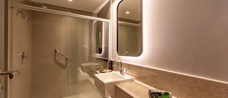 Un baño moderno con ducha de mampara de vidrio, lavabo y espejo de tocador.