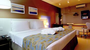 Ein Hotelzimmer mit Bett, Nachttisch, Lampe und Schreibtisch mit Stuhl.