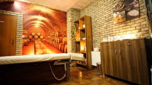 A spa room with a massage table, a brick wall mural, a wooden cabinet, and a tiled floor. - Hotel Vestil (Piotrkow Trybunalski)