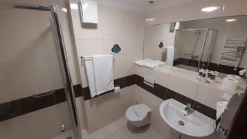 Ein modernes Badezimmer mit Duschkabine aus Glas, einem weißen Waschbecken und einer Toilette.