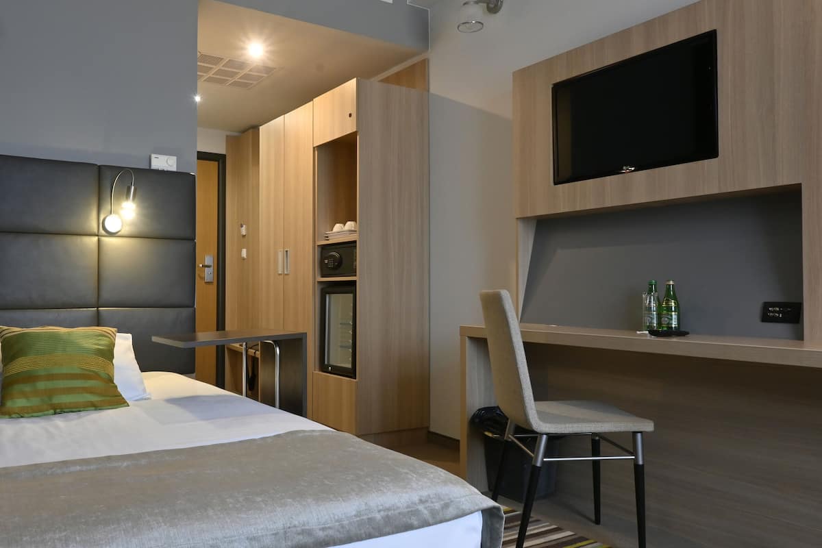 Une chambre d’hôtel moderne équipée d’un lit, d’un bureau, d’une chaise, d’une télévision et d’un four à micro-ondes.