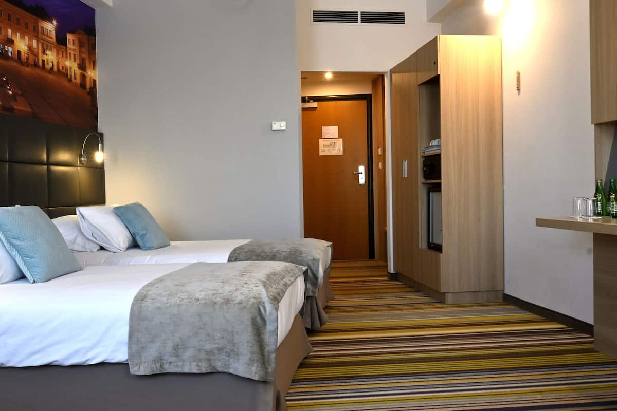 Une chambre d’hôtel avec deux lits, une télévision, un minibar et vue sur la rue.