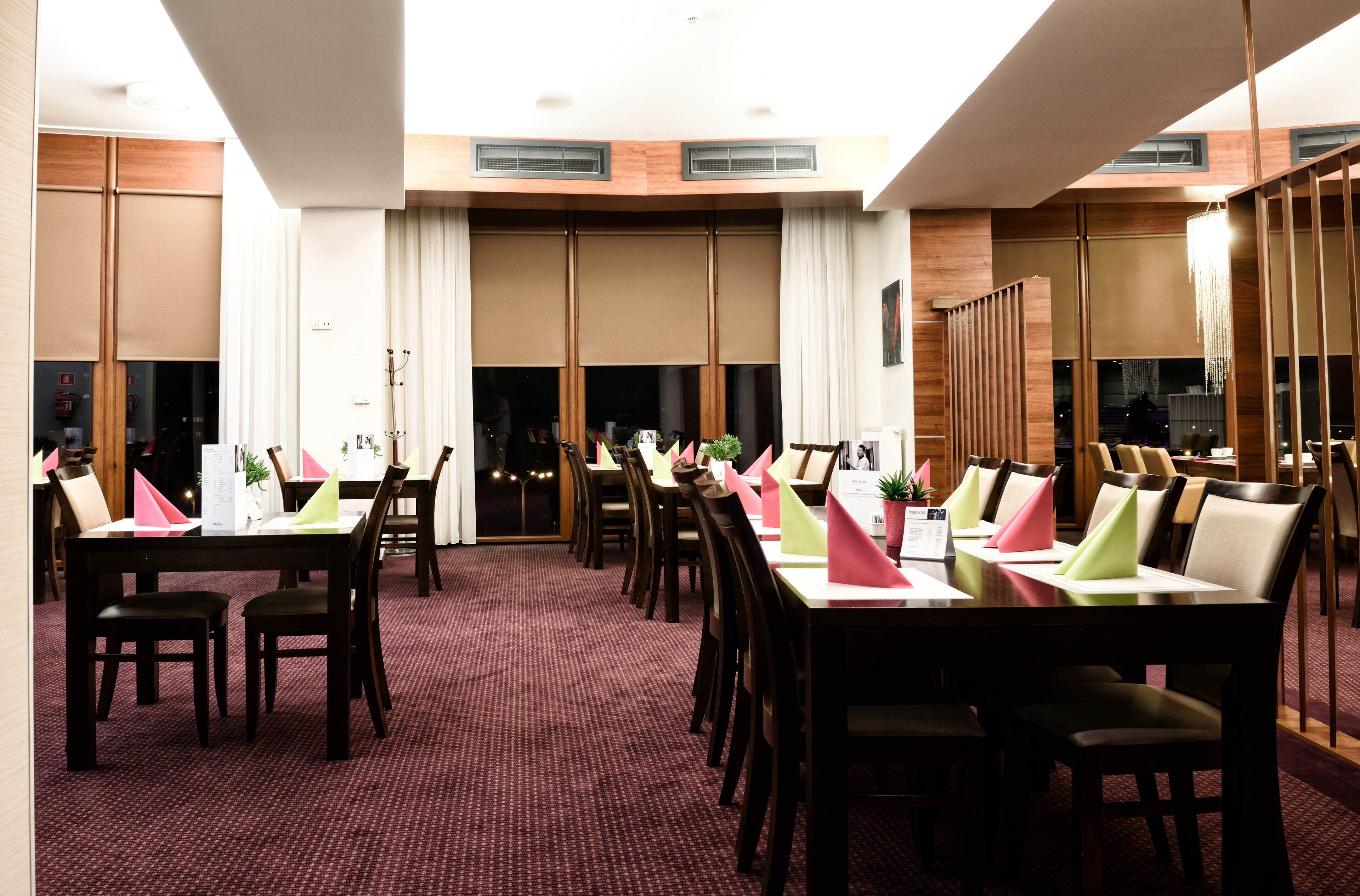 Une salle de conférence dotée de plusieurs tables et chaises, de grandes fenêtres et d’un plafond haut.