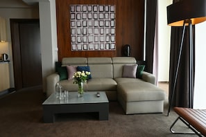 A modern living room with a sectional sofa, a coffee table, and a decorative wall panel. - Hotel Vestil (Piotrkow Trybunalski)