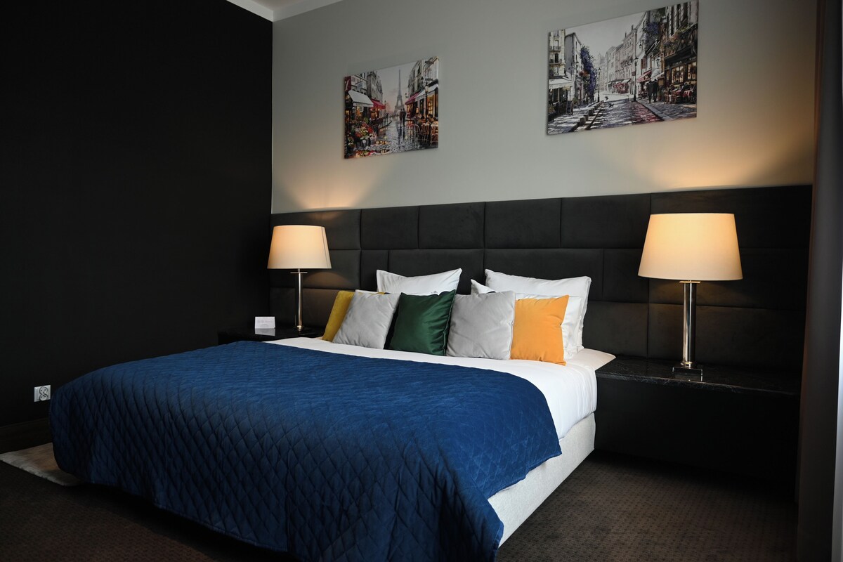 Une chambre d’hôtel avec un grand lit, deux lampes de chevet et deux tableaux accrochés au mur.