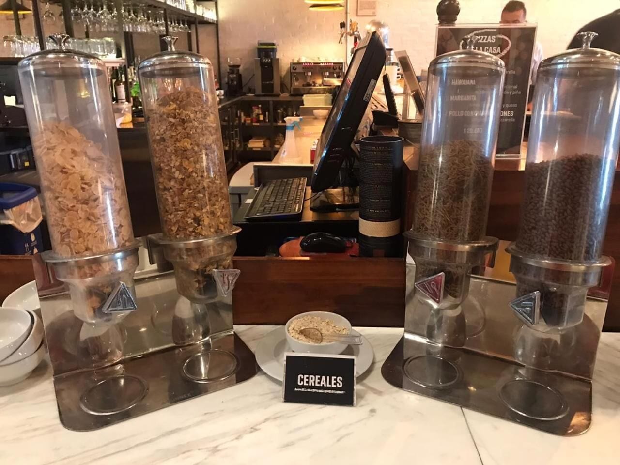 Uma barra de cereais com quatro distribuidores identificados por diferentes tipos de cereal.
