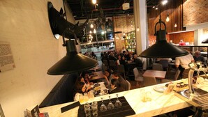 Un restaurante con barra, mesas y comensales.