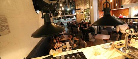 A restaurant with a bar area, tables, and patrons.