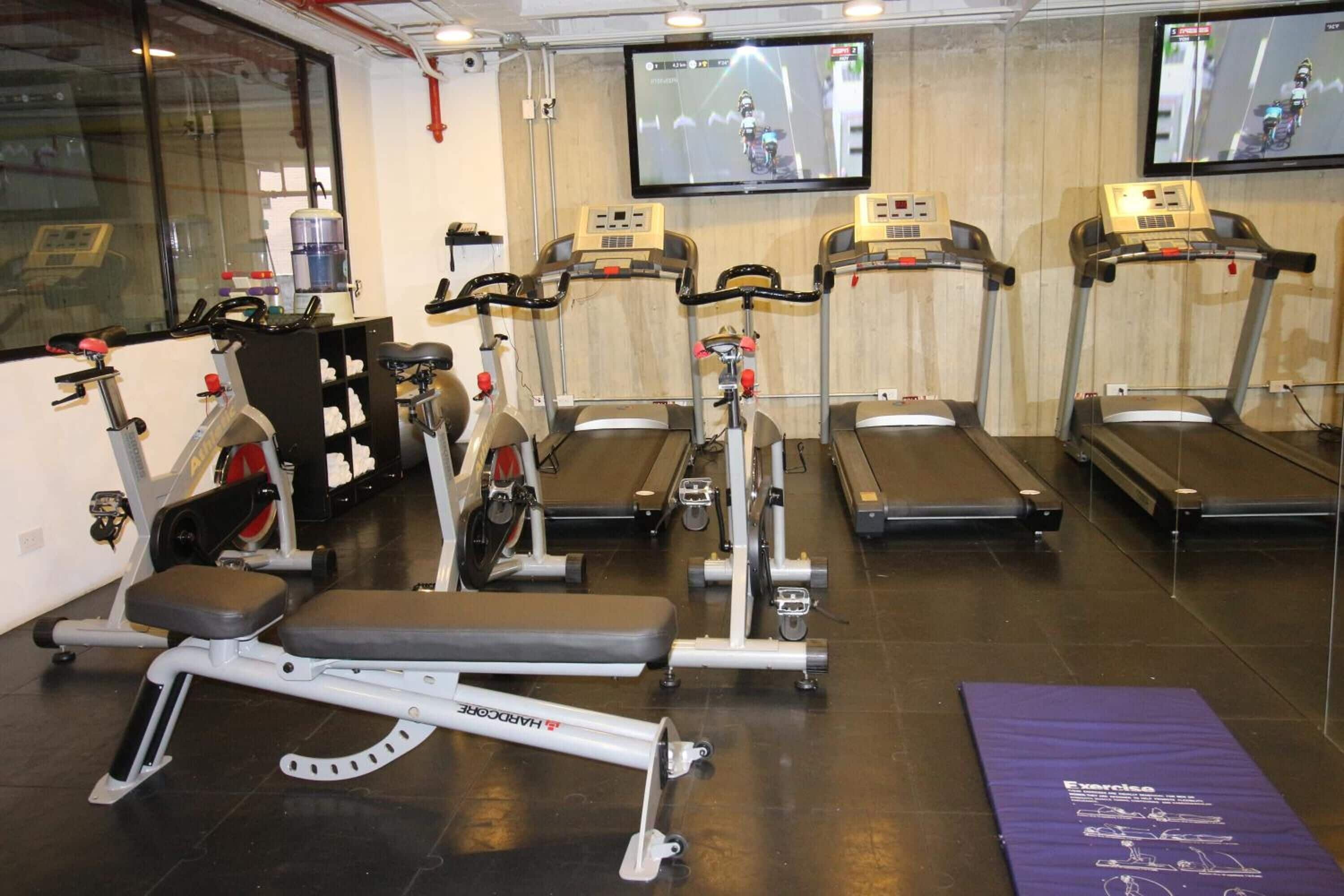 Un gimnasio con cintas de correr, bicicletas estáticas y máquinas de pesas.