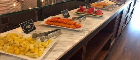 A buffet counter with various fruits and a sign indicating 'PINA'.