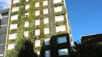 A tall building with a facade covered in greenery and multiple windows.