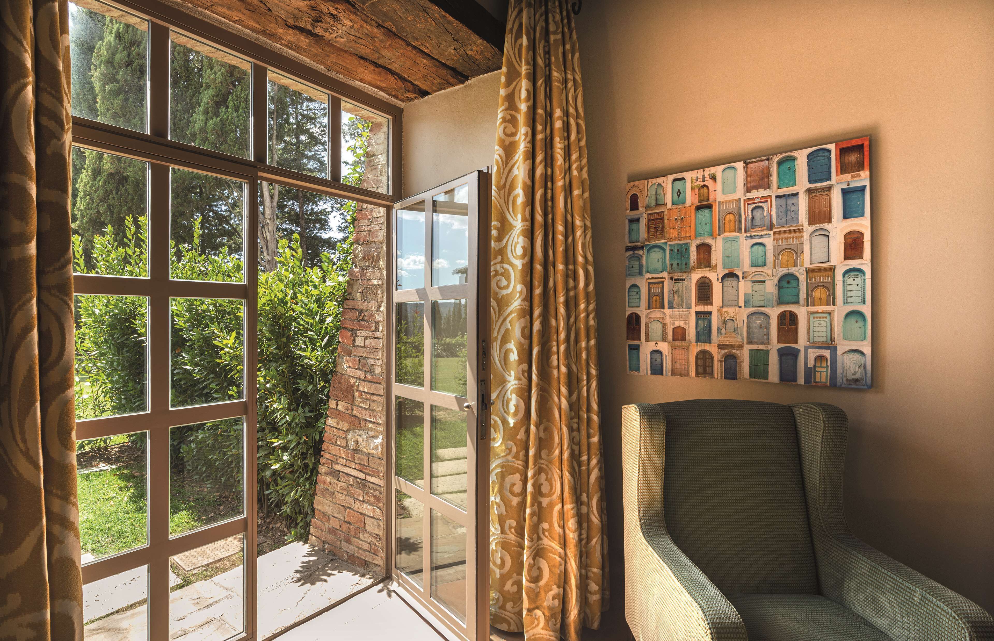 Ein Zimmer mit einem großen Fenster, einem Sessel und einer Wand voller gerahmter Bilder.