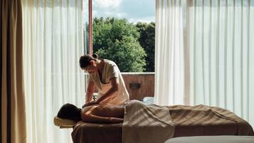 A massage therapy room with a massage table, a client lying face down, and a therapist attending to the client.