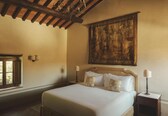 A bedroom with a large bed, a wooden ceiling, a painting on the wall, and a window with curtains.