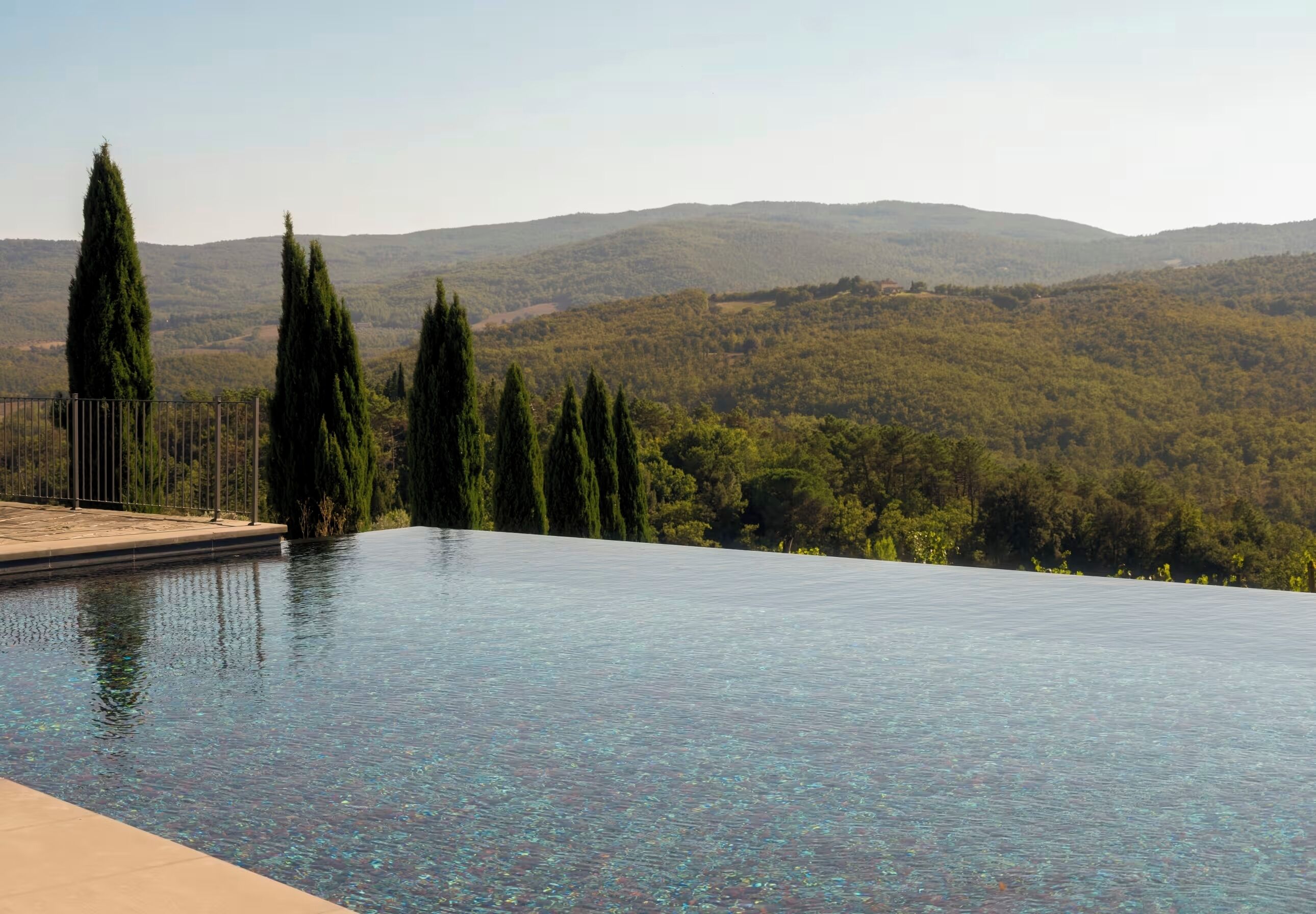 Ein Infinity-Pool mit Blick auf einen bewaldeten Hügel.