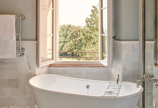 A bathroom with a freestanding bathtub, a window with a view of trees, and a shower area.