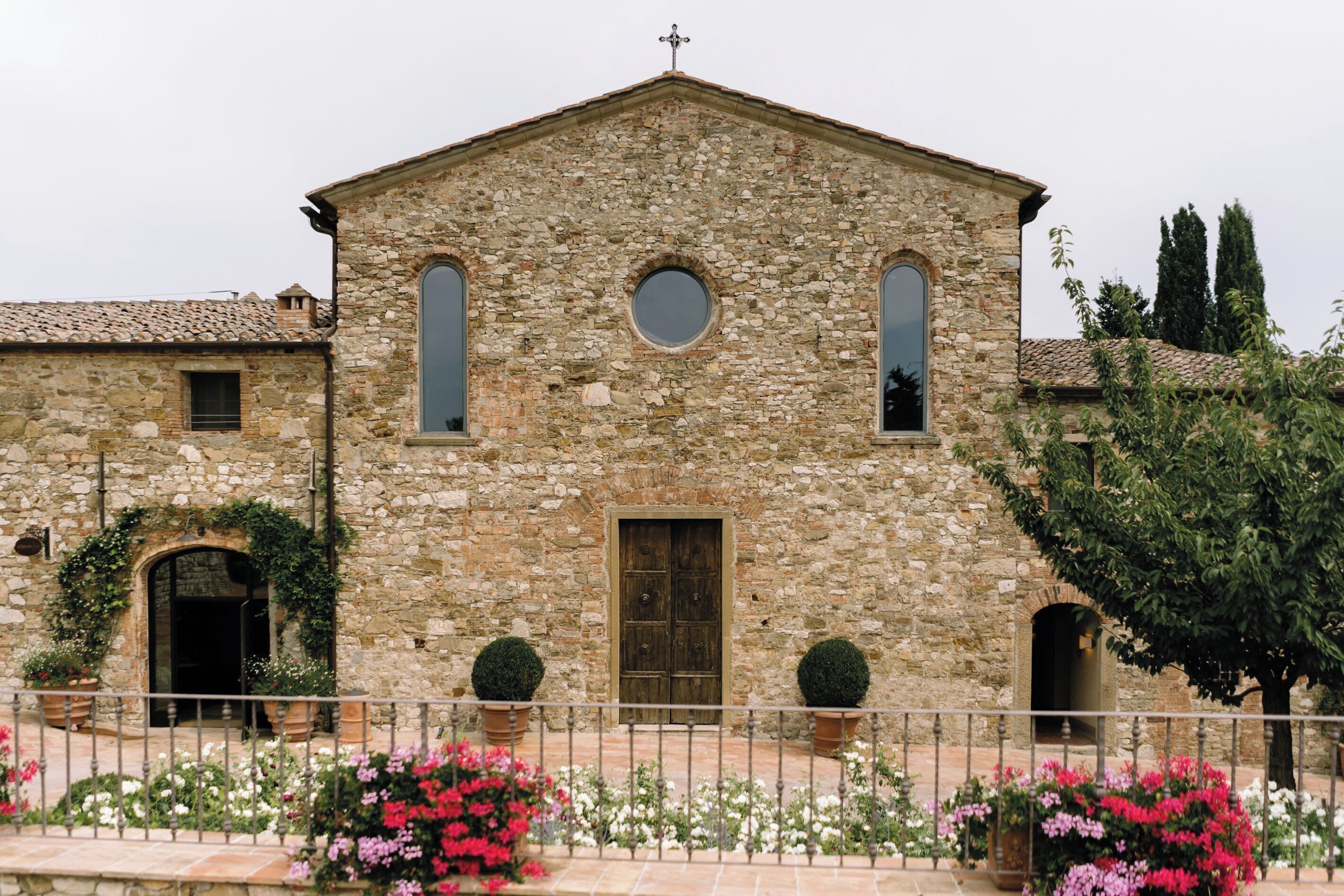Un edificio de piedra con una puerta central, dos ventanas en arco y una ventana circular pequeña encima de la puerta.