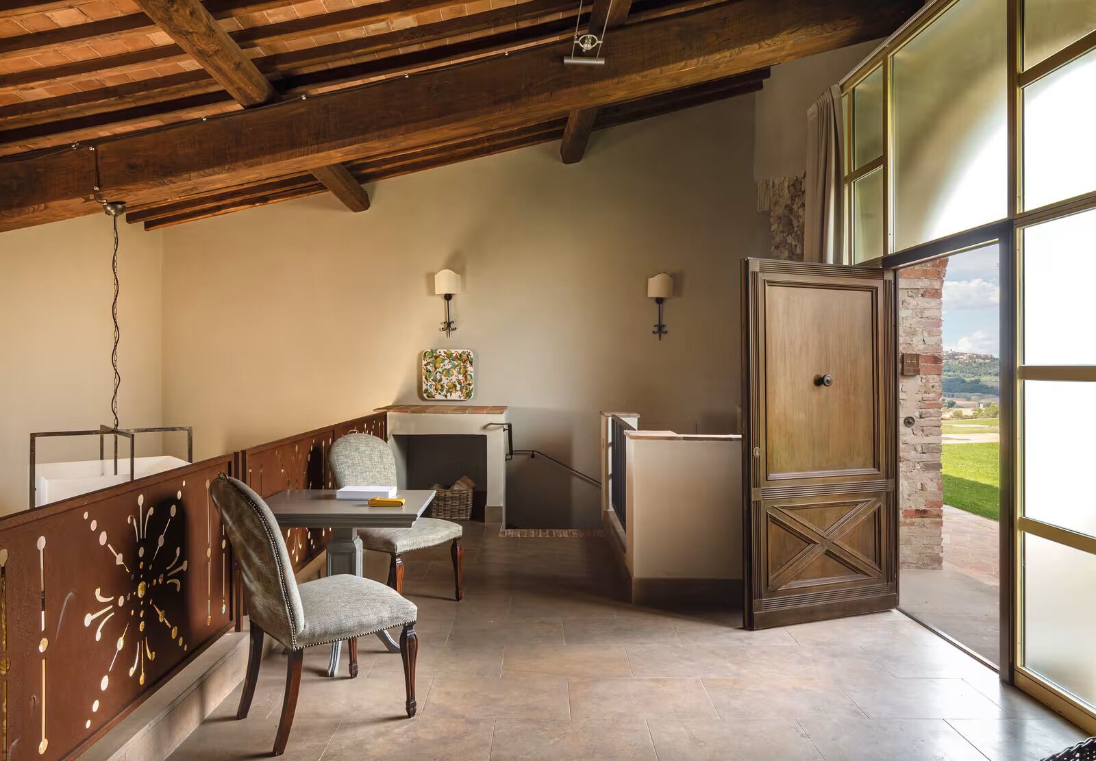 Une pièce spacieuse avec un plafond haut, une cheminée, un coin repas avec une table et des chaises, et une grande fenêtre donnant sur l’extérieur.