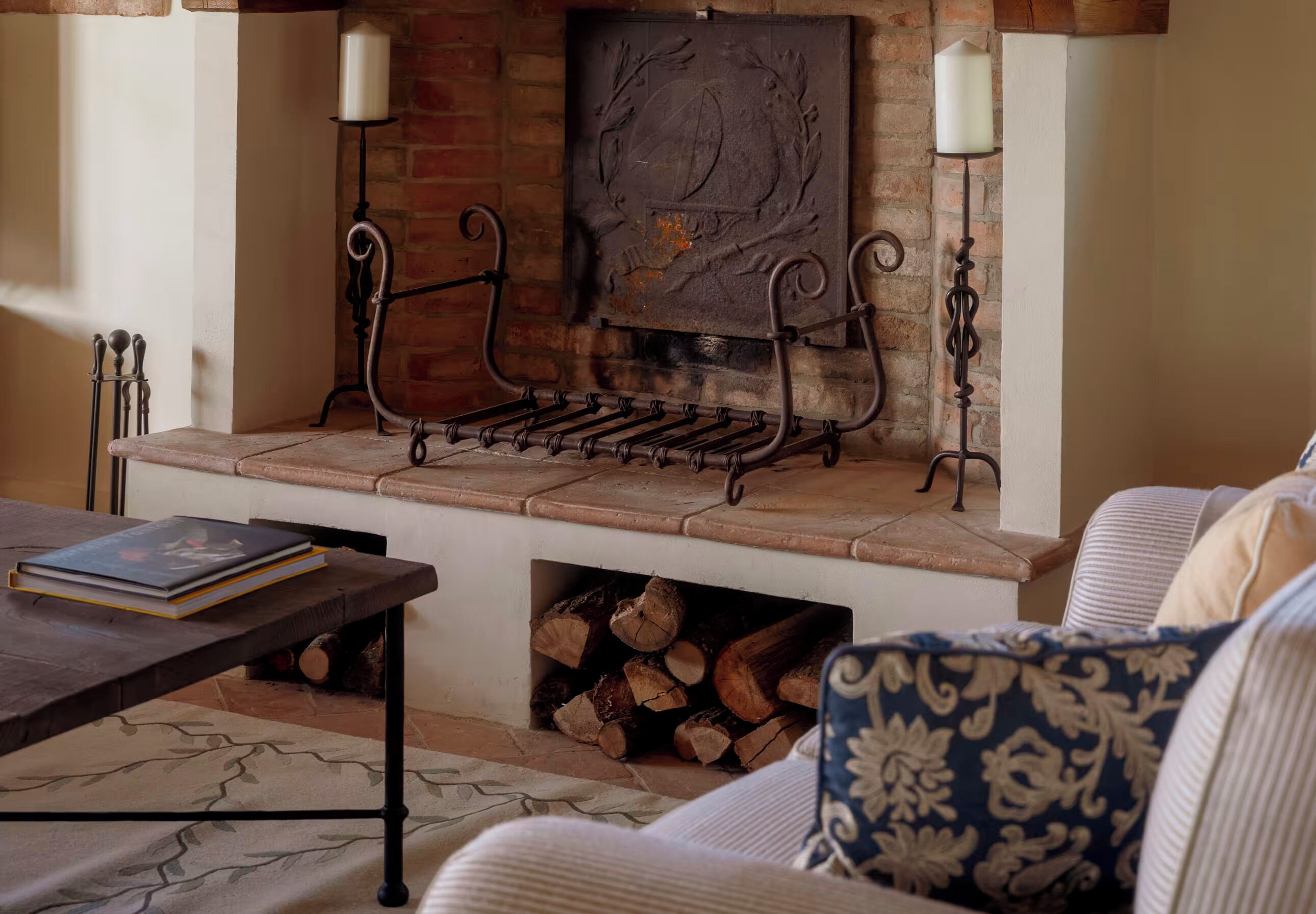 A cozy living room with a fireplace, a coffee table, and a sofa with patterned cushions.
