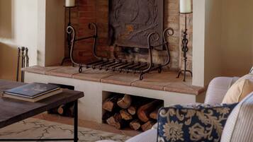 A cozy living room with a fireplace, a coffee table, and a sofa with patterned cushions.