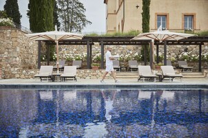 Una piscina al aire libre, sombrillas, sillones reclinables de piscina